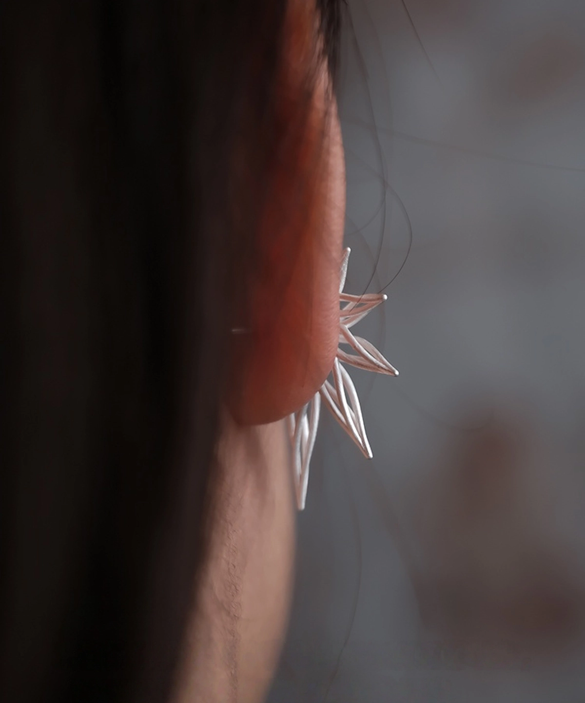 Back view of an ear adorned with Dancing Petals-Organic Sterling Silver Statement Earrings, highlighting its elegant curvature and organic petal-inspired design.
