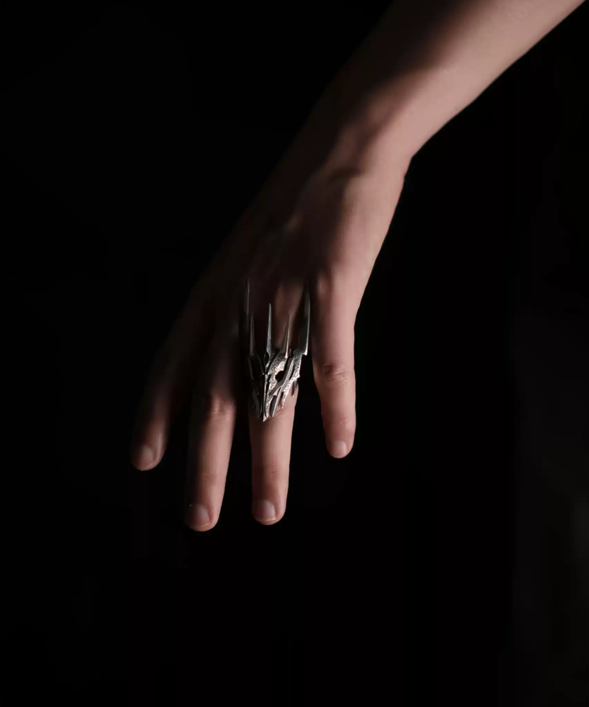 A hand wearing the Dark Lord Ring for Men, a 925 Sterling Silver Gothic Armor Ring inspired by Sauron from The Lord of the Rings. The ring features intricate, spiked designs resembling armor.