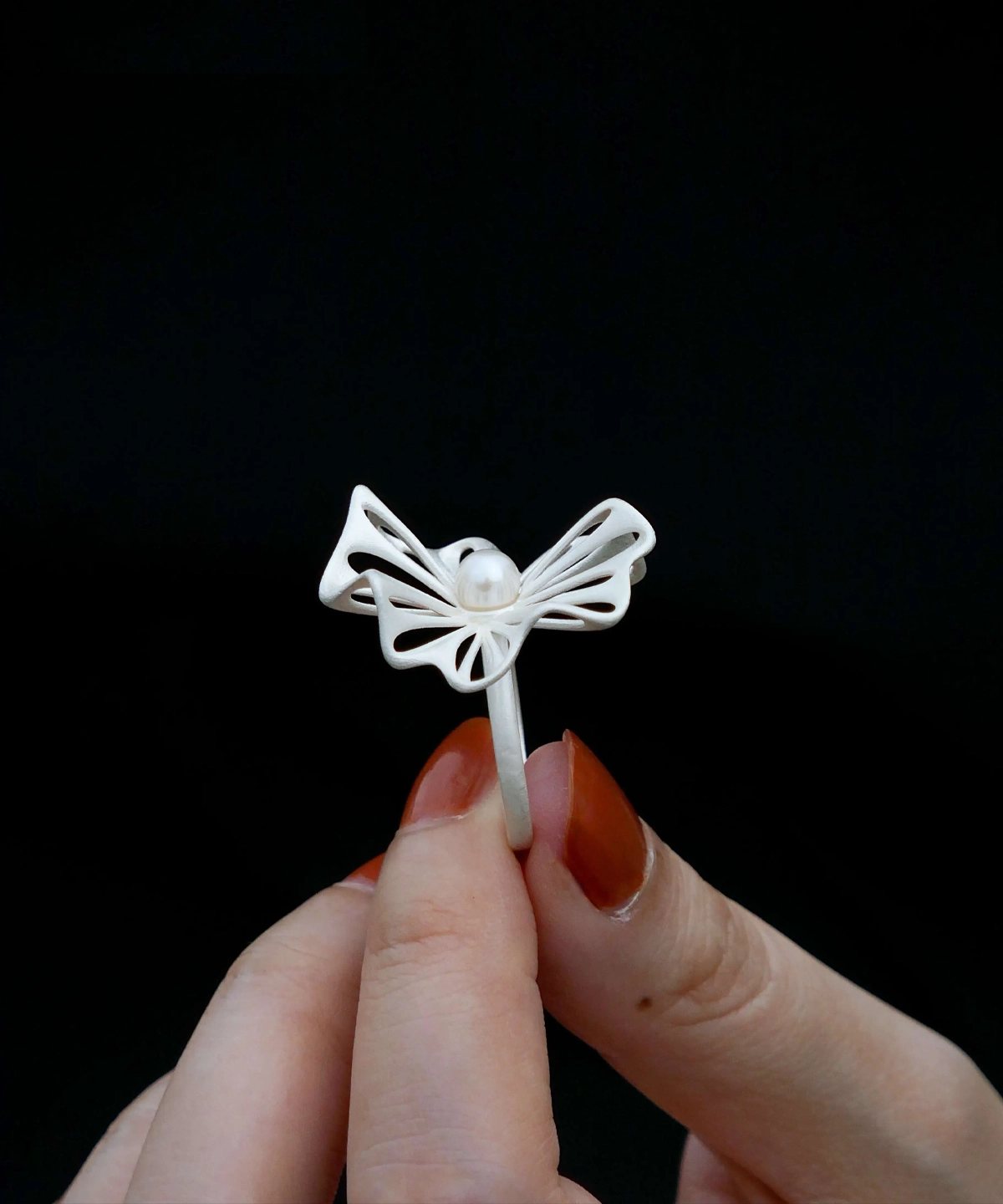 A stylish hand holds a 925 silver adjustable leaf ring with a freshwater pearl, showcasing its intricate leaf design and delicate craftsmanship. The ring’s adjustable band ensures a comfortable fit, making it a versatile and elegant accessory for any occasion. Perfect for nature-inspired jewelry lovers.