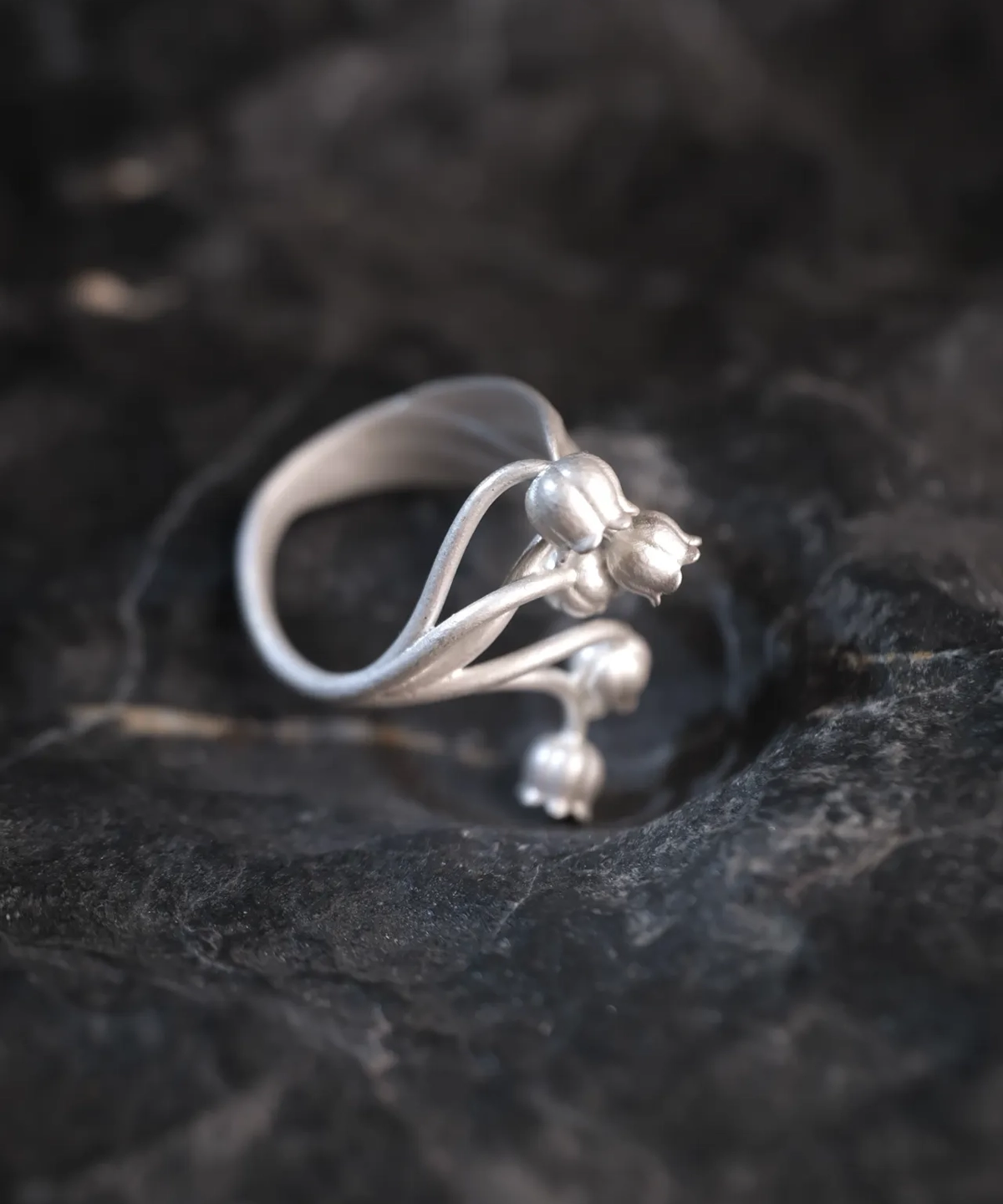 A close-up image of a Lily of the Valley Ring made from S925 sterling silver. The ring features delicate, handcrafted lily of the valley flowers and an adjustable open design.