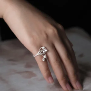 A close-up image of a hand wearing the Lily of the Valley Ring, an S925 sterling silver open ring. The ring features delicate silver flowers resembling lily of the valley blooms.