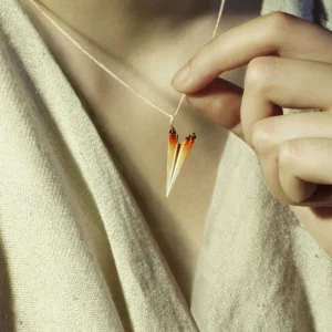 Close-up of a person wearing a Paper Airplane Necklace made of S925 Sterling Silver. The necklace features a single detailed paper airplane pendant with a gradient color from silver to orange at the tips.