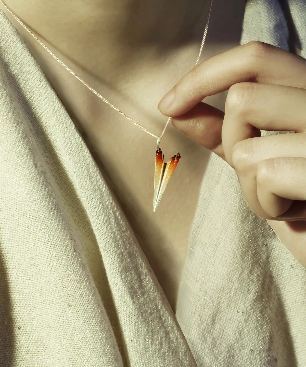 Close-up of a person wearing a Paper Airplane Necklace made of S925 Sterling Silver. The necklace features a single detailed paper airplane pendant with a gradient color from silver to orange at the tips.