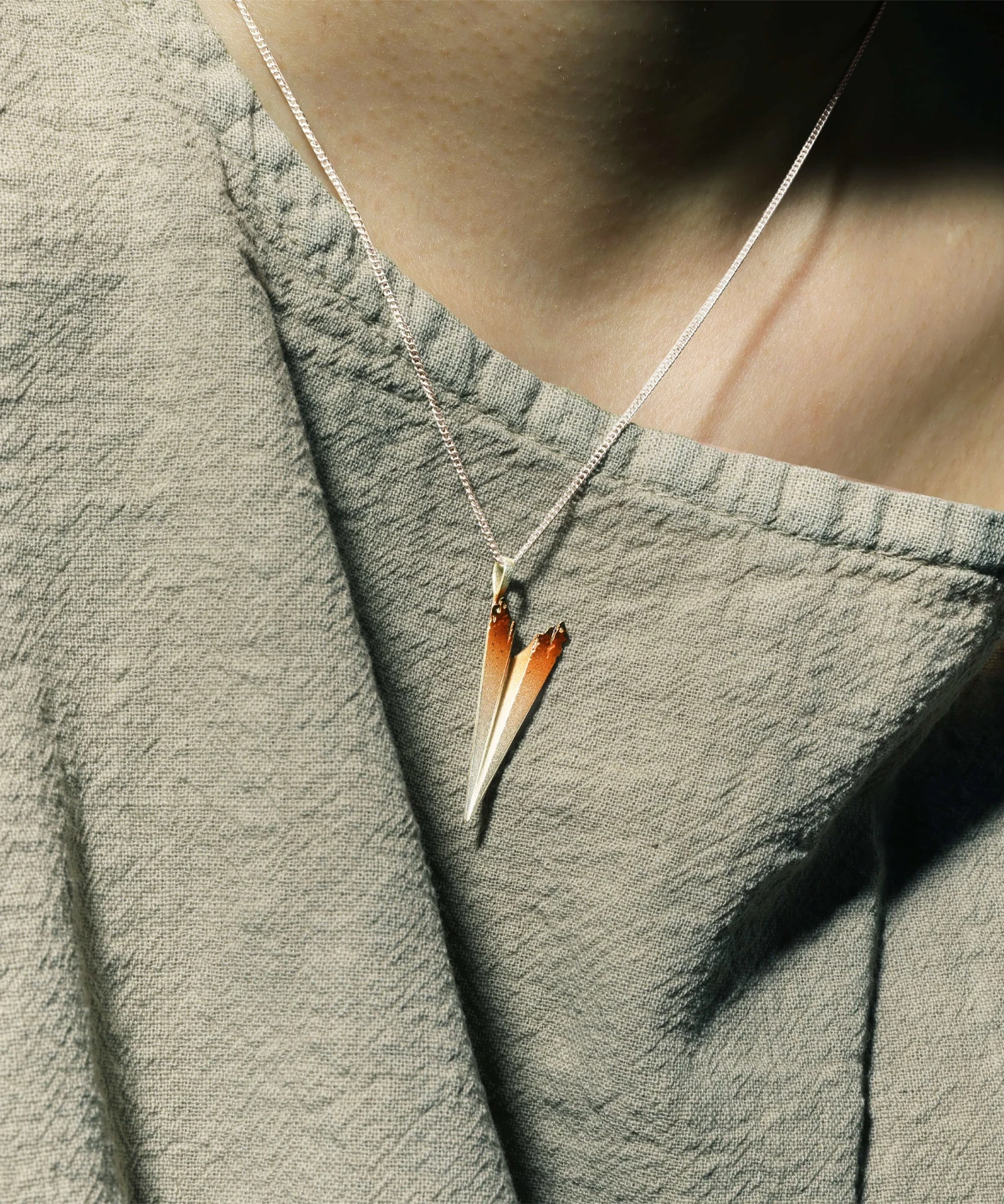 A close-up of a Paper Airplane Necklace made from S925 Sterling Silver, featuring a minimalist yet elegant design. The delicate chain holds a handcrafted paper airplane pendant with a gradient color transition from silver to gold, capturing its unique artistic craftsmanship.