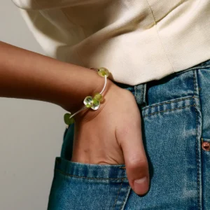 A stylish woman's hand rests casually in a pocket, adorned with the Lazesoul Prelude Summer Peridot Bracelet—crafted from S925 sterling silver with natural prehnite and peridot beads; handmade elegance captured in detail.
