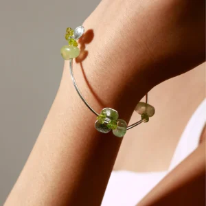 Elegant close-up of a wrist wearing the Prelude Summer Peridot Bracelet, handcrafted in S925 sterling silver with natural green prehnite and peridot stones, highlighting its artisan charm and luminous gemstone details.
