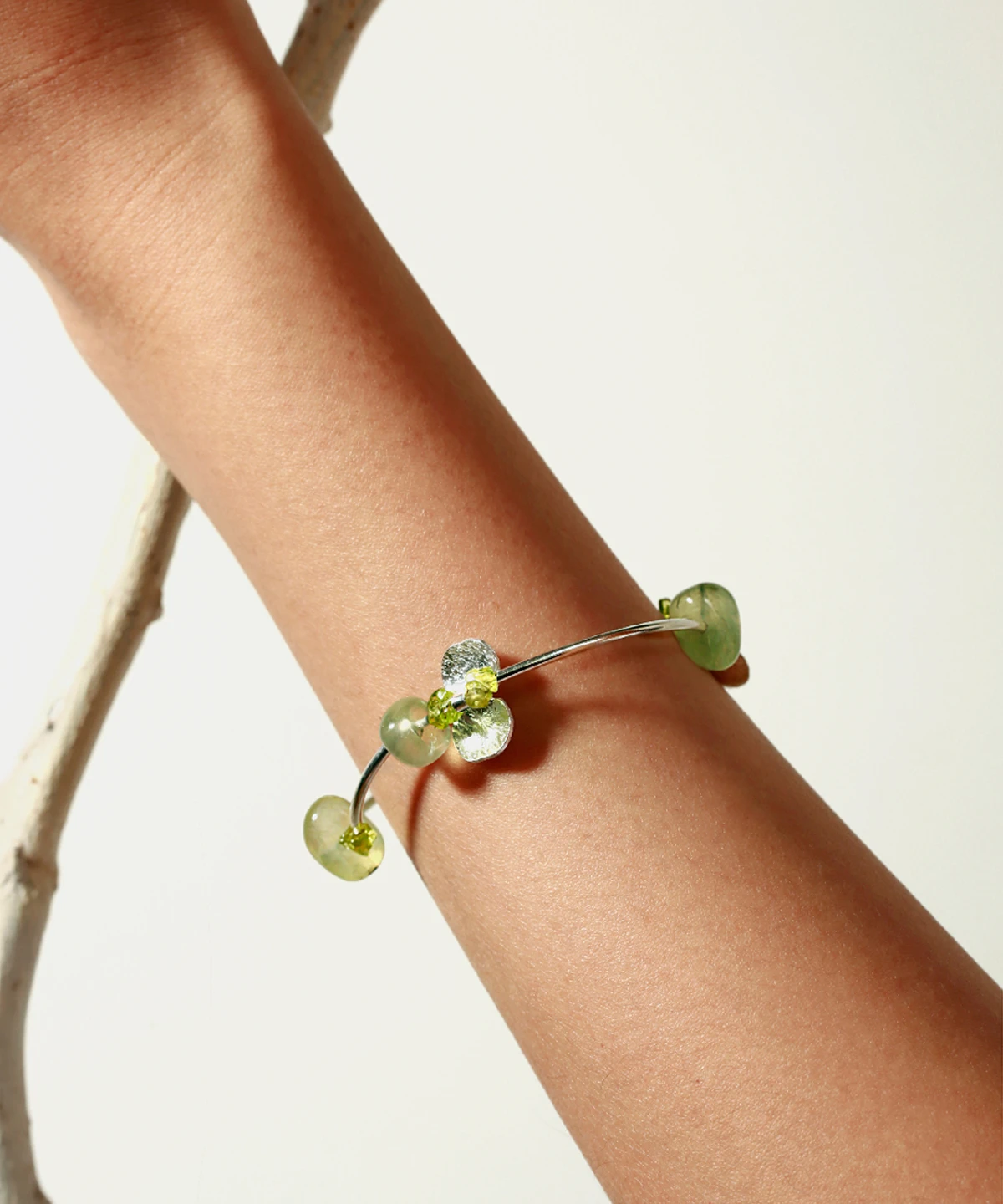 A close-up of the Prelude Summer natural peridot bracelet in sterling silver worn on a wrist, featuring handcrafted green prehnite and peridot stones from Lazesoul. Elegant and minimal jewelry for summer styling. Peridot Bracelet, handmade jewelry.