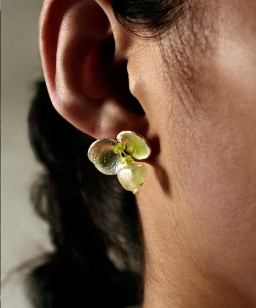 A close-up of a woman wearing Lazesoul's Prelude Summer natural peridot earrings in sterling silver, handcrafted with S925 silver and featuring luminous green prehnite and peridot gemstones.