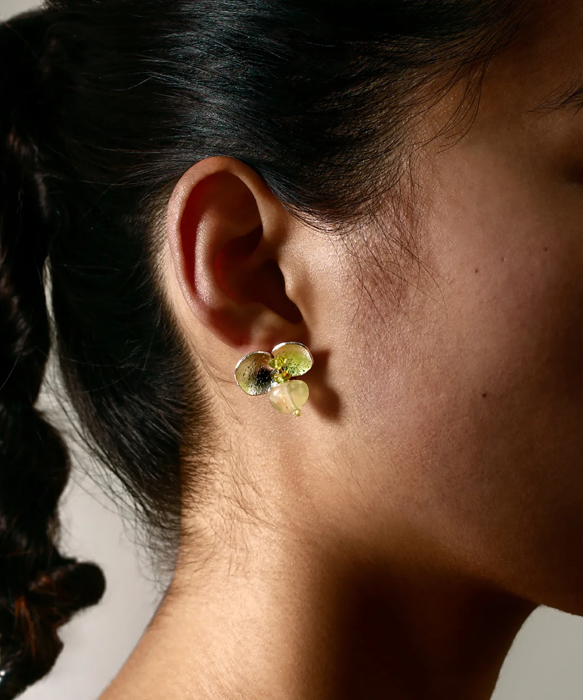 A close-up of a woman wearing Lazesoul's Prelude Summer natural peridot earrings in sterling silver, handcrafted with S925 silver and featuring luminous green prehnite and peridot gemstones.