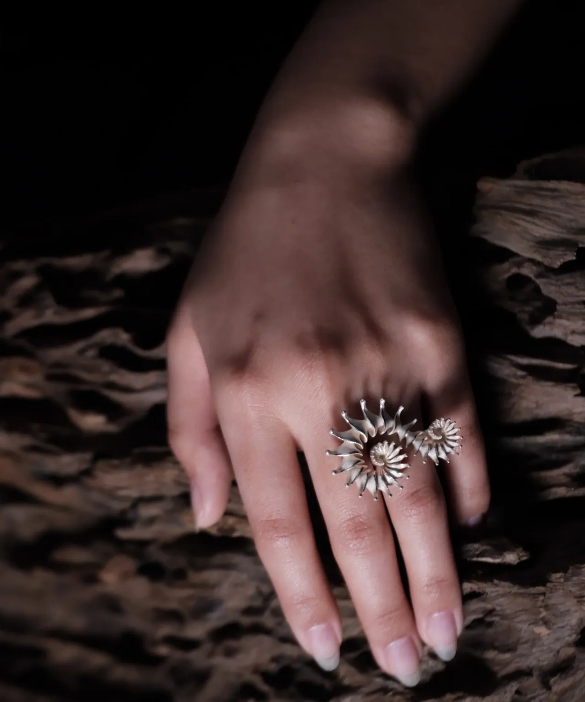 The Spiral Ring embodies modern artistry, seamlessly merging elegance with craftsmanship. Handmade in S925 sterling silver, this design ring features a sculptural spiral motif, creating a striking visual flow. The close-up image captures the ring’s refined details, worn gracefully on the hand, with a natural wooden texture enhancing its organic aesthetic. A statement piece designed for those who appreciate timeless sophistication and intricate design.