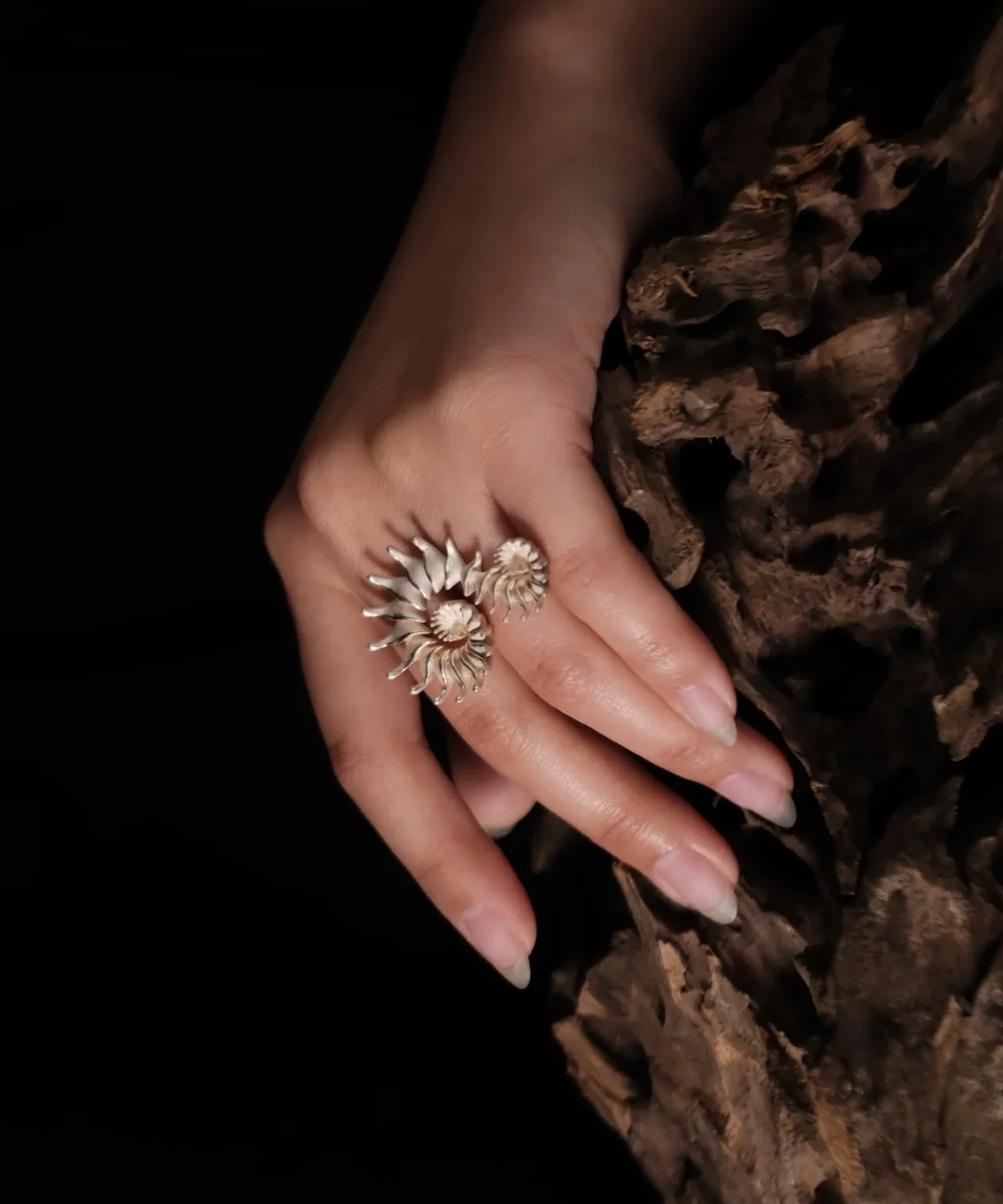 The Spiral Ring embodies modern artistry, seamlessly merging elegance with craftsmanship. Handmade in S925 sterling silver, this design ring features a sculptural spiral motif, creating a striking visual flow. The close-up image captures the ring’s refined details, worn gracefully on the hand, with a natural wooden texture enhancing its organic aesthetic. A statement piece designed for those who appreciate timeless sophistication and intricate design.