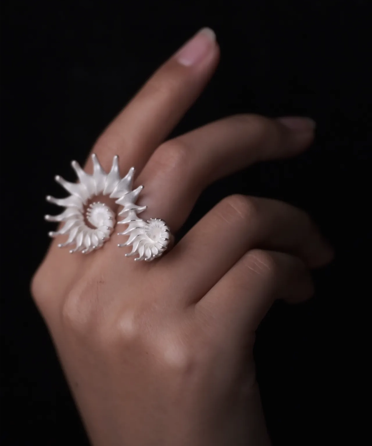 A close-up of a hand adorned with a Spiral Ring, crafted in S925 sterling silver, showcasing its sculptural and artistic design. The fluid, intertwined curves wrap elegantly around two fingers, creating a bold yet sophisticated statement.