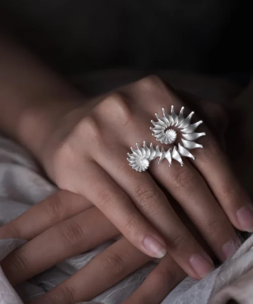 A close-up of a hand wearing a Spiral Ring, crafted from S925 sterling silver. The sculptural design features elegant curves that evoke movement and fluidity, making this design ring a striking statement piece. The polished finish highlights its artistry, seamlessly blending contemporary minimalism with handmade craftsmanship.