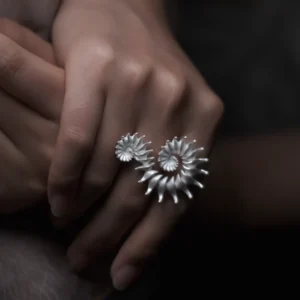 A close-up of a hand elegantly adorned with the Spiral Ring, a S925 sterling silver design ring. The sculptural piece features twin spirals, reflecting artisanal craftsmanship and timeless style.