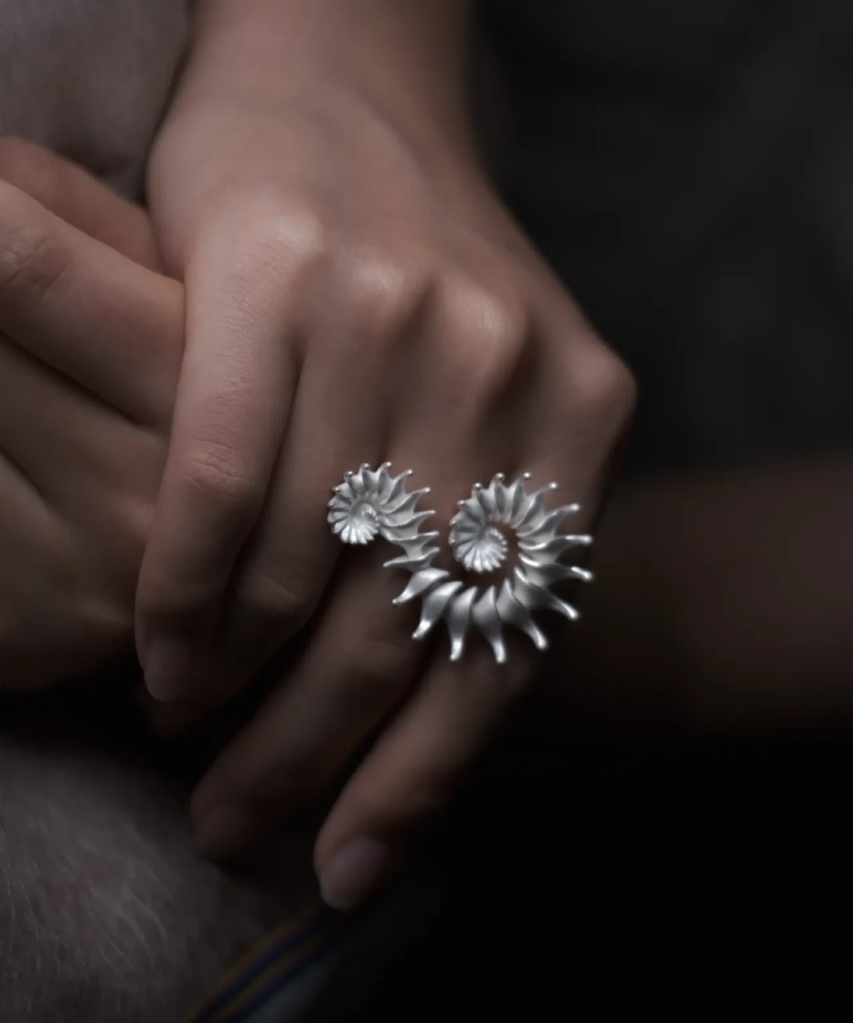 A close-up of a hand elegantly adorned with the Spiral Ring, a S925 sterling silver design ring. The sculptural piece features twin spirals, reflecting artisanal craftsmanship and timeless style.