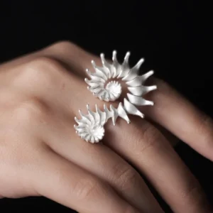 A close-up of a hand adorned with a Spiral Ring, crafted in S925 sterling silver, showcasing its sculptural and artistic design. The fluid, intertwined curves wrap elegantly around two fingers, creating a bold yet sophisticated statement.