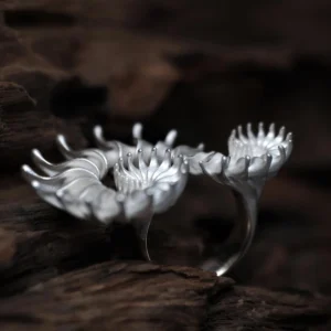 A handcrafted Spiral Ring made of S925 sterling silver, featuring three intricate spiral flower-like structures with delicately curved petals. The sculptural design highlights organic fluidity and artistic craftsmanship. Set against a textured wooden background, the ring's polished finish and dimensional form showcase elegance and sophistication, embodying the essence of a statement Design Ring.