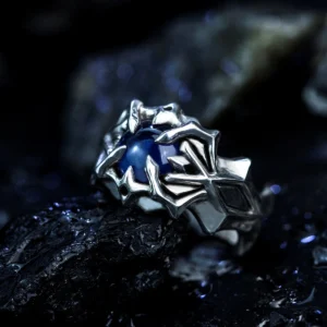 A close-up image of the Vongola Ring Of Hell, a handmade sterling silver ring featuring a natural blue spinel gemstone. Inspired by Mukuro Rokudo from Katekyo Hitman Reborn, the ring showcases intricate details and craftsmanship against a dark, rocky background.