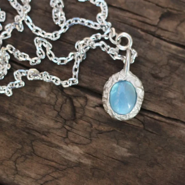 925 Silver Natural Aquamarine Necklace 04 Close-up view of Lazesoul's handmade 925 Silver Natural Aquamarine Necklace featuring an oval-cut aquamarine gemstone set in S925 sterling silver, displayed on rustic wood to highlight the craftsmanship and elegance of natural gemstone jewelry.