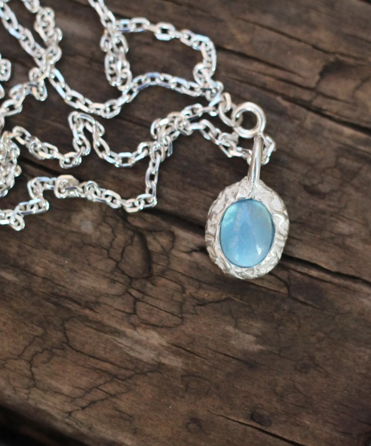 Close-up view of Lazesoul's handmade 925 Silver Natural Aquamarine Necklace featuring an oval-cut aquamarine gemstone set in S925 sterling silver, displayed on rustic wood to highlight the craftsmanship and elegance of natural gemstone jewelry.