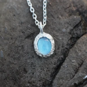 Close-up view of a handmade 925 silver natural aquamarine necklace featuring a light blue gemstone pendant on a textured stone background — Lazesoul jewelry, elegant and minimalist.