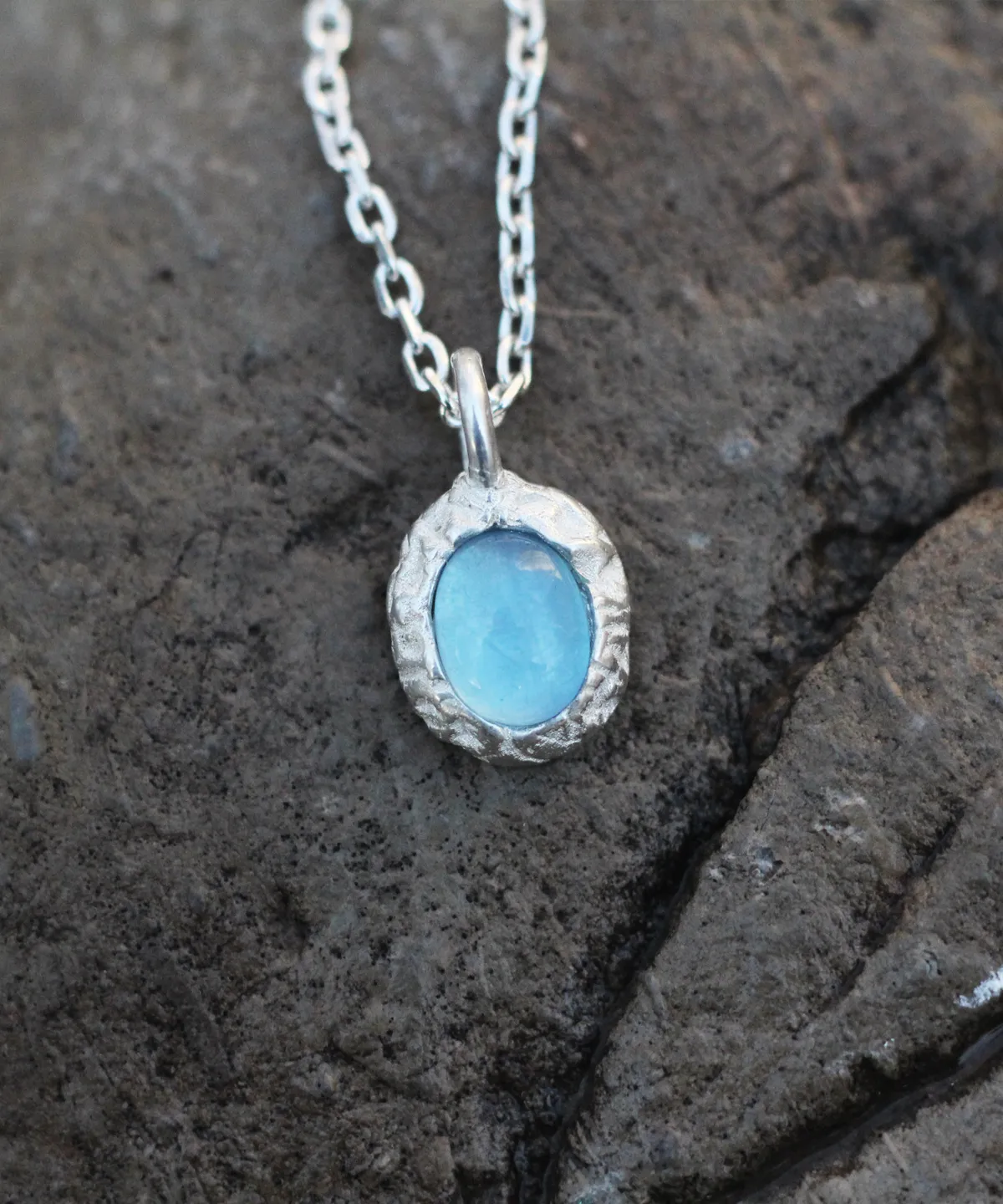 Close-up view of a handmade 925 silver natural aquamarine necklace featuring a light blue gemstone pendant on a textured stone background — Lazesoul jewelry, elegant and minimalist.