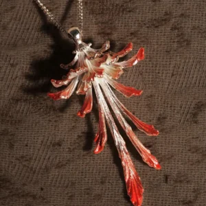 Drooping Blossom | 925 Sterling Silver Long Necklace features a stunning floral pendant with cascading, elongated petals that shift from a luminous metallic silver to rich reddish-orange tips. Suspended from a sleek sterling silver chain and set against a dark, textured backdrop, this statement piece exudes refined elegance and modern sophistication. Ideal for both formal occasions and everyday wear, it highlights exceptional craftsmanship and timeless allure.