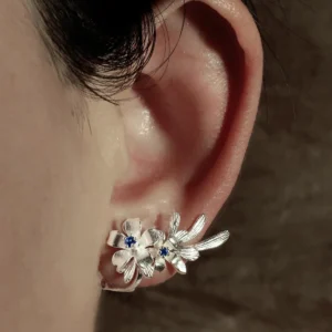 Close-up of a person's ear wearing Lazesoul’s Lily Earrings—S925 sterling silver ear cuffs featuring lab-created sapphire in delicate lily flower design, handmade for natural elegance.