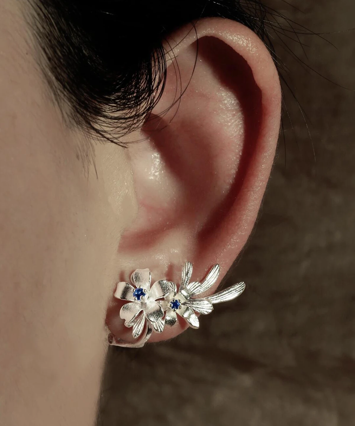 Close-up of a person's ear wearing Lazesoul’s Lily Earrings—S925 sterling silver ear cuffs featuring lab-created sapphire in delicate lily flower design, handmade for natural elegance.