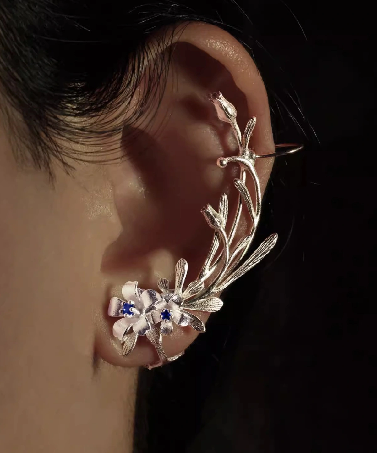 Close-up of an ear wearing Lazesoul’s handmade Lily Earrings, crafted in S925 sterling silver with intricate lily-shaped details and shimmering lab-created sapphires. Elegant ear cuff highlights floral artistry and natural elegance.