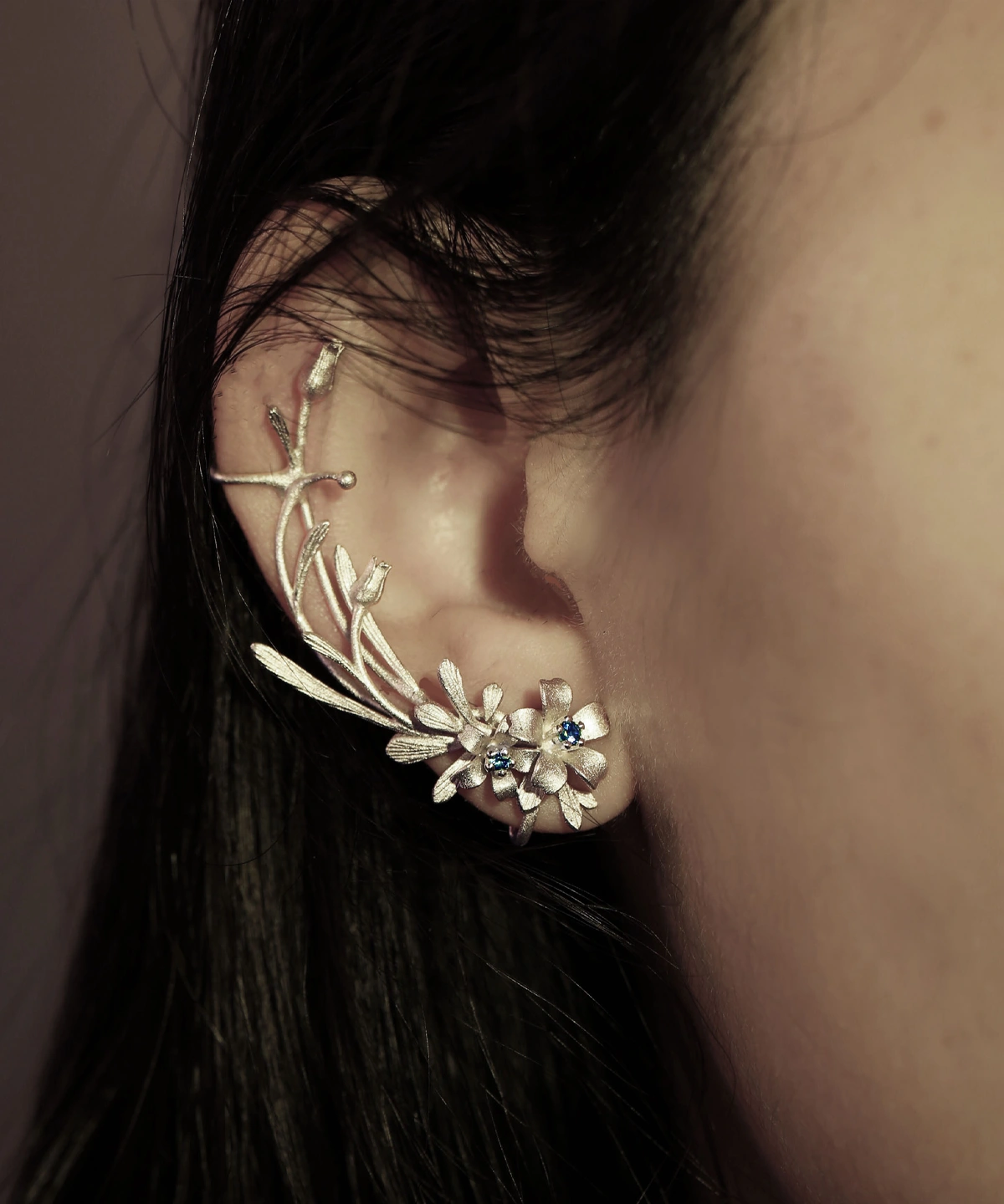 Close-up of ear wearing Lazesoul's Lily Earrings-S925 Sterling Silver Ear Cuff, featuring delicate lily-inspired floral motifs and lab-created sapphire accents; elegant handmade jewelry in natural style.