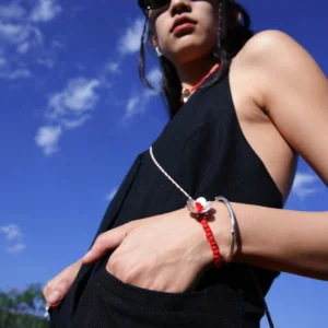 Handmade beaded ring bracelet featuring a sterling silver flower charm and red glaze beads, worn with a black outfit against a blue sky; Lazesoul's S925 sterling silver jewelry.