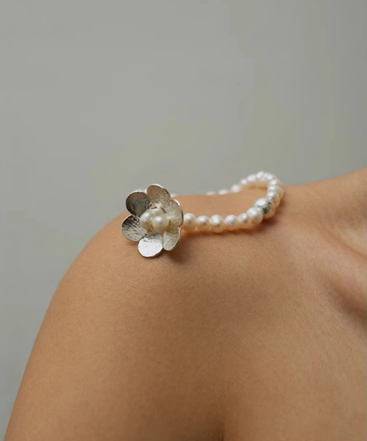 Close-up of Lazesoul’s Little Flower Beaded Bracelet in S925 Sterling Silver, with natural freshwater pearls and floral silver accents, styled on a shoulder; a handmade beaded ring bracelet combining elegance with artisanal craftsmanship.