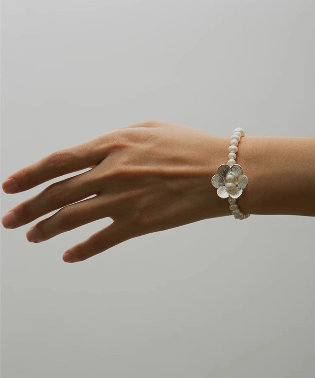 Hand wearing Lazesoul's Little Flower Beaded Bracelet crafted in S925 sterling silver with natural freshwater pearls and floral accents. A delicately handmade Beaded Ring style perfect for nature-inspired jewelry lovers.