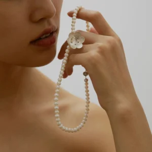 Hand holding Lazesoul Handmade S925 Sterling Silver Little Flower Beaded Necklace with natural freshwater pearl beads and an intricately detailed silver flower charm. The elegant beaded necklace drapes gracefully against a soft neutral background.