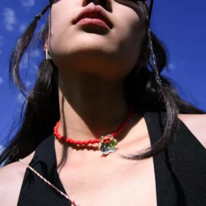 A woman models a Lazesoul handmade beaded necklace featuring a S925 sterling silver flower pendant and vivid red glaze beads, set against a blue sky for a natural, elegant backdrop.
