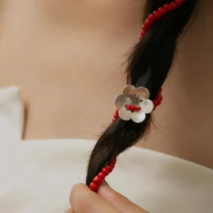 Close-up of a braid adorned with Lazesoul’s Little Flower Beaded Necklace in S925 Sterling Silver. Features red glaze beads and a silver flower charm, showcasing elegant craftsmanship and natural styling.