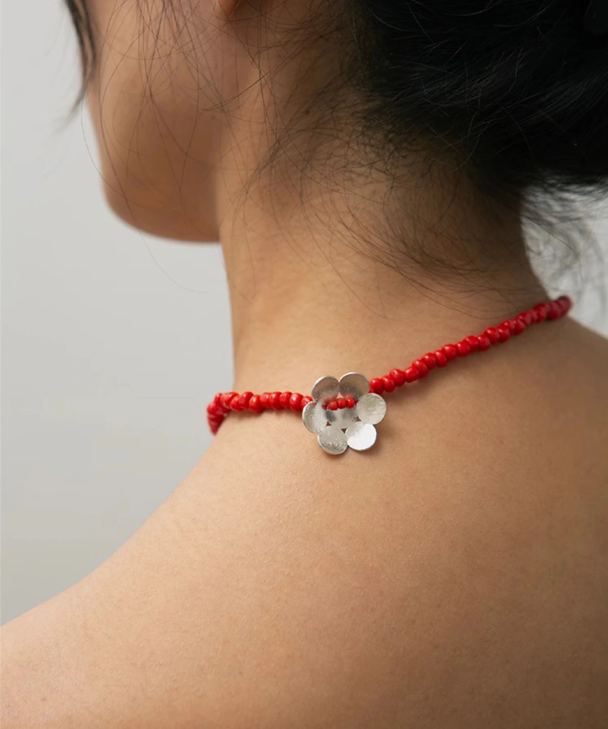 Close-up of Lazesoul Handmade Natural Jewelry’s Little Flower Beaded Necklace in S925 Sterling Silver, featuring red glaze beads. The delicate floral design and beadwork rest elegantly around the model’s neck, perfect for nature-inspired styling.