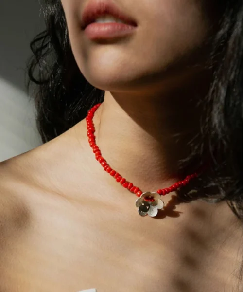 A handmade beaded necklace with a red glaze bead and a delicate sterling silver flower pendant, elegantly worn on the neck, showcasing Lazesoul’s artisanal craftsmanship in S925 sterling silver jewelry.
