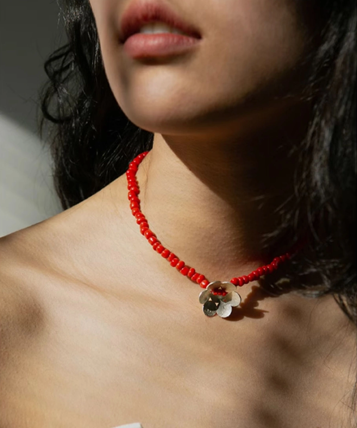 A handmade beaded necklace with a red glaze bead and a delicate sterling silver flower pendant, elegantly worn on the neck, showcasing Lazesoul’s artisanal craftsmanship in S925 sterling silver jewelry.