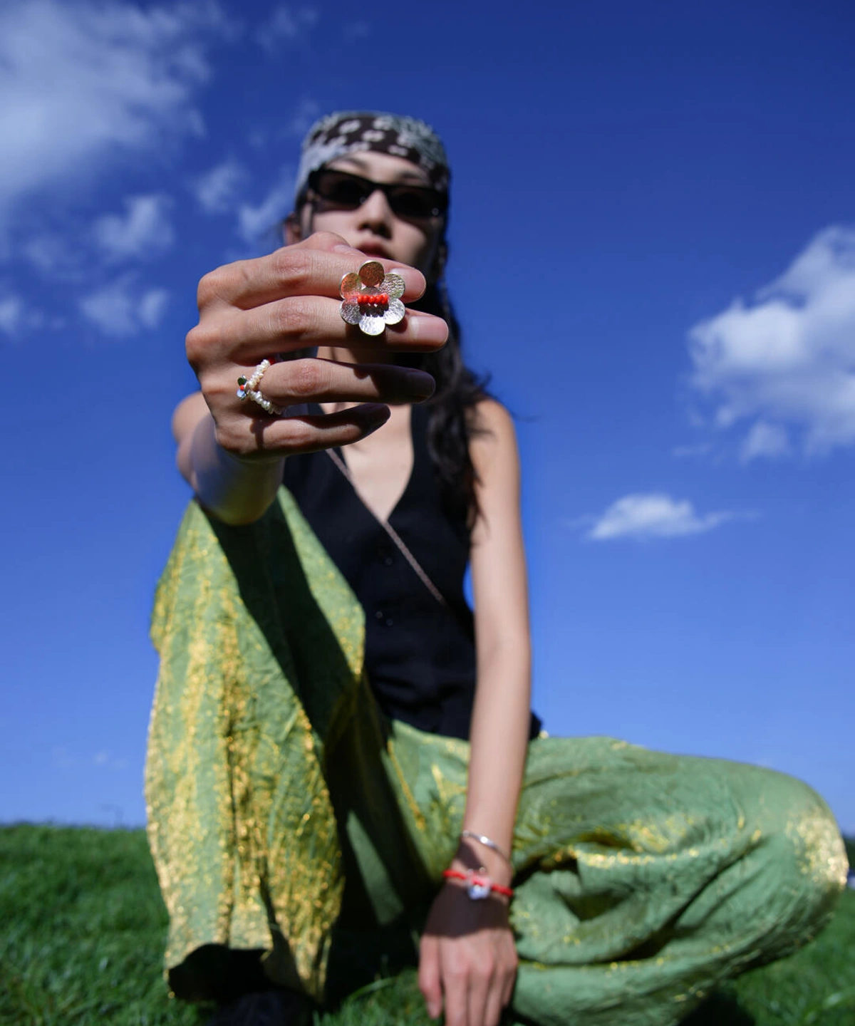 Hand wearing Lazesoul’s Little Flower Beaded Ring in S925 Sterling Silver, featuring a red glaze bead centered in a delicate floral design. Styled outdoors with green pants and a black top.