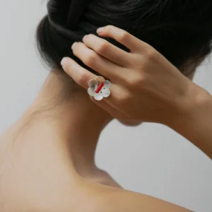 A handmade little flower beaded ring in S925 sterling silver with a red glaze bead, worn on the left hand. The elegant natural jewelry piece is from Lazesoul and crafted with delicate artisanal detail.