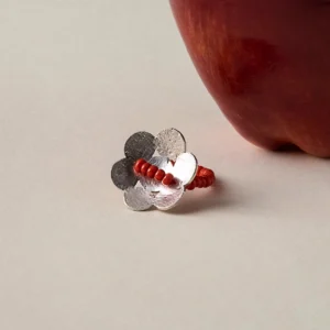 Handmade beaded ring in S925 sterling silver with a red glaze flower design, positioned beside a red apple to highlight its natural elegance and artisan craftsmanship.