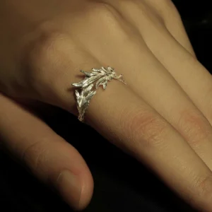 Close-up of a hand wearing the New Leaf Adjustable Sterling Silver Leaf Ring from Lazesoul Handmade Natural Jewelry. The silver ring features a nature-inspired branch design with high shine against a dark background, emphasizing elegance.