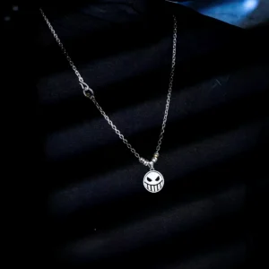 A close-up view of a S925 Silver Pirate Necklace featuring a reversible Laugh & Cry Face Spinner Pendant, worn against a dark, shadowed background; handmade anime jewelry inspired by One Piece.