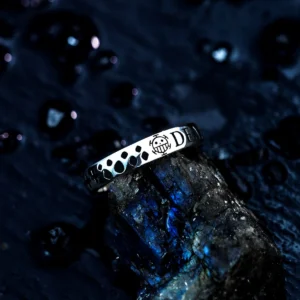 Close-up of a Lazesoul handmade S925 sterling silver pirates ring with a bold skull emblem and engraved word “DEATH,” resting on a moody, water-speckled background. A detailed One Piece-inspired accessory for anime fans. Keywords: Pirates Ring
