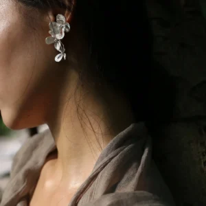 Close-up of a woman wearing Lazesoul Handmade Natural Jewelry's Sterling Silver Filigree Blossom Earrings, featuring intricate floral filigree in S925 silver with a graceful ear cuff and drop earring combination.
