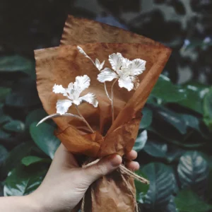 Hand holding a rustic-wrapped Iris Bouquet with delicate white flowers, symbolizing purity and elegance. Perfect as handmade Art Gifts, featuring Lazesoul’s 925 Sterling Silver Mini Iris Bouquet design.