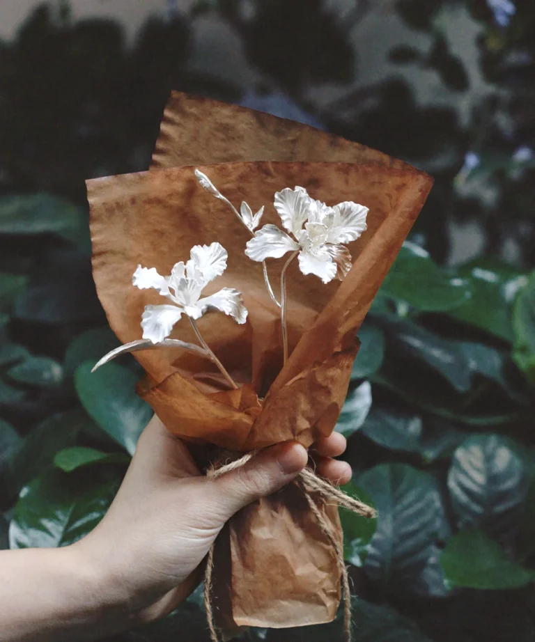 Hand holding a rustic-wrapped Iris Bouquet with delicate white flowers, symbolizing purity and elegance. Perfect as handmade Art Gifts, featuring Lazesoul’s 925 Sterling Silver Mini Iris Bouquet design.