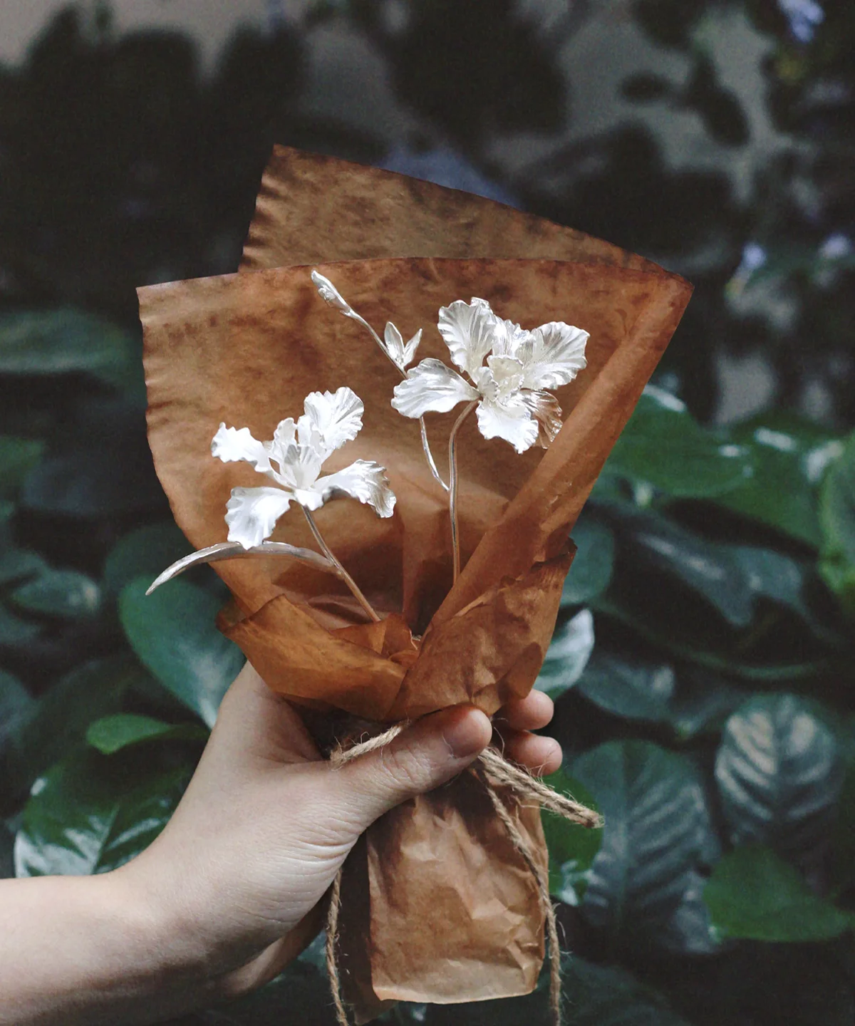 Hand holding a rustic-wrapped Iris Bouquet with delicate white flowers, symbolizing purity and elegance. Perfect as handmade Art Gifts, featuring Lazesoul’s 925 Sterling Silver Mini Iris Bouquet design.